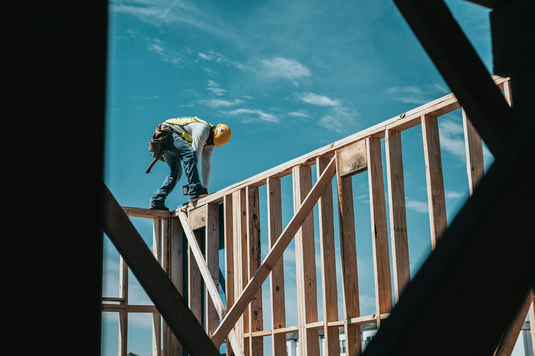 Carpenter working on a timber frame against an open sky.