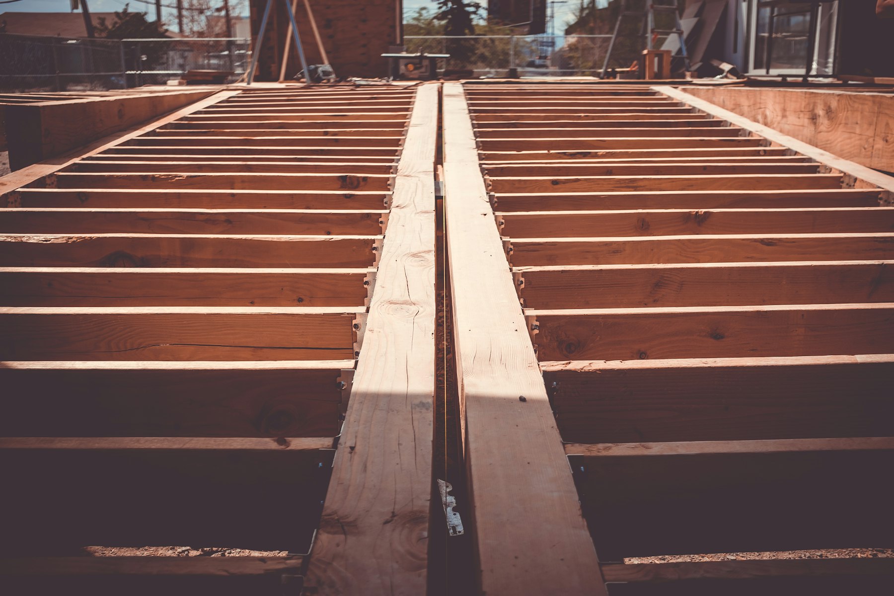 Floor joists receding into shadow inside an unfinished house.