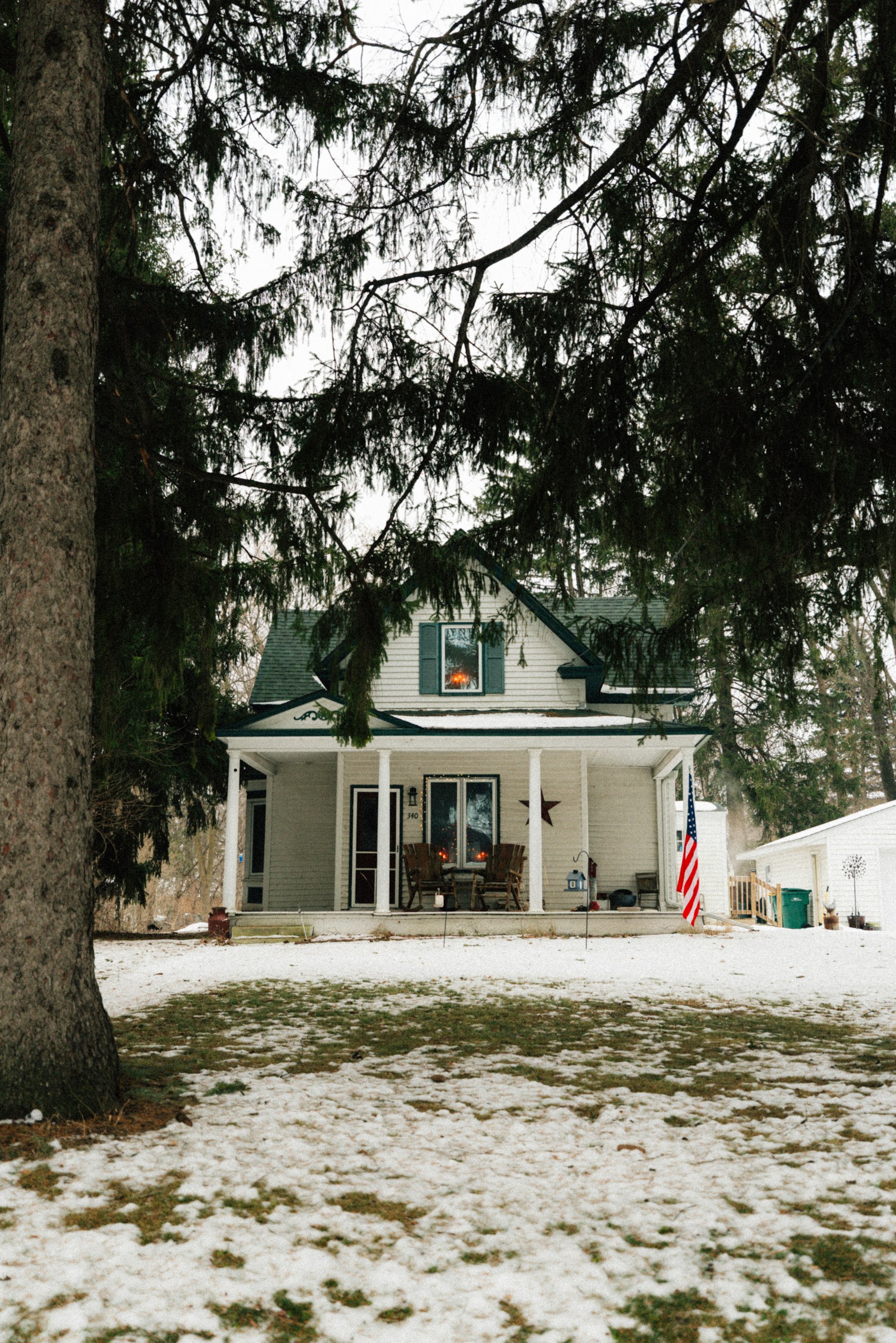 A white farmhouse with a long front porch on a clear day.
